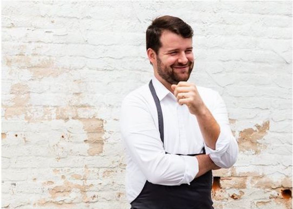 a man standing in front of a brick wall