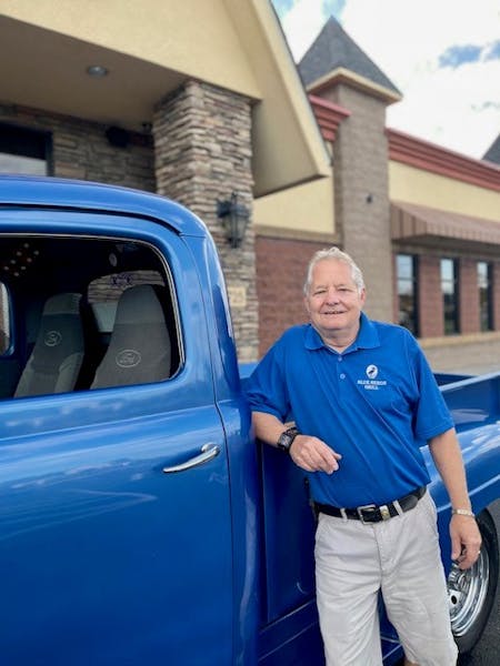 a man standing in front of a blue car
