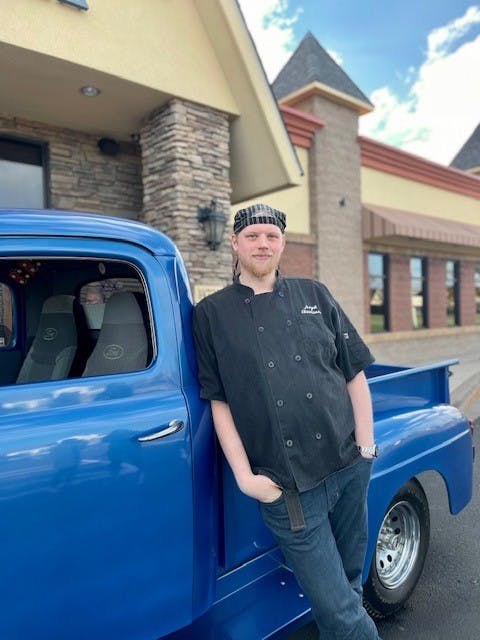 a man standing in front of a blue car