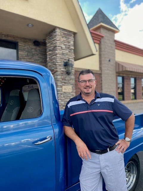 a man standing in front of a blue car