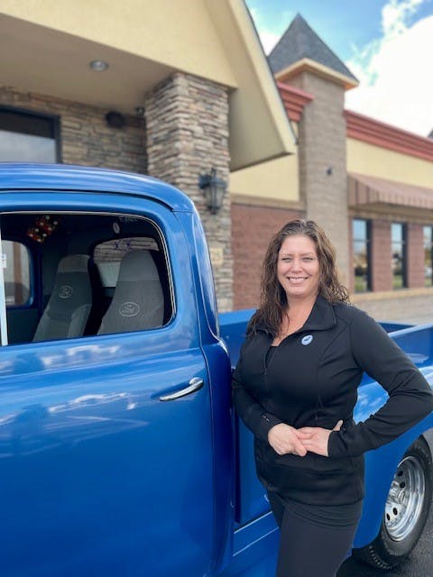 a person standing in front of a blue car