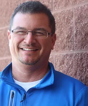a man wearing glasses and smiling at the camera