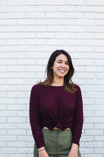a woman standing in front of a brick wall