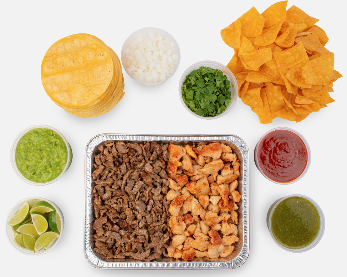 A tray of meat with tortillas, chips, sauces, onion and cilantro