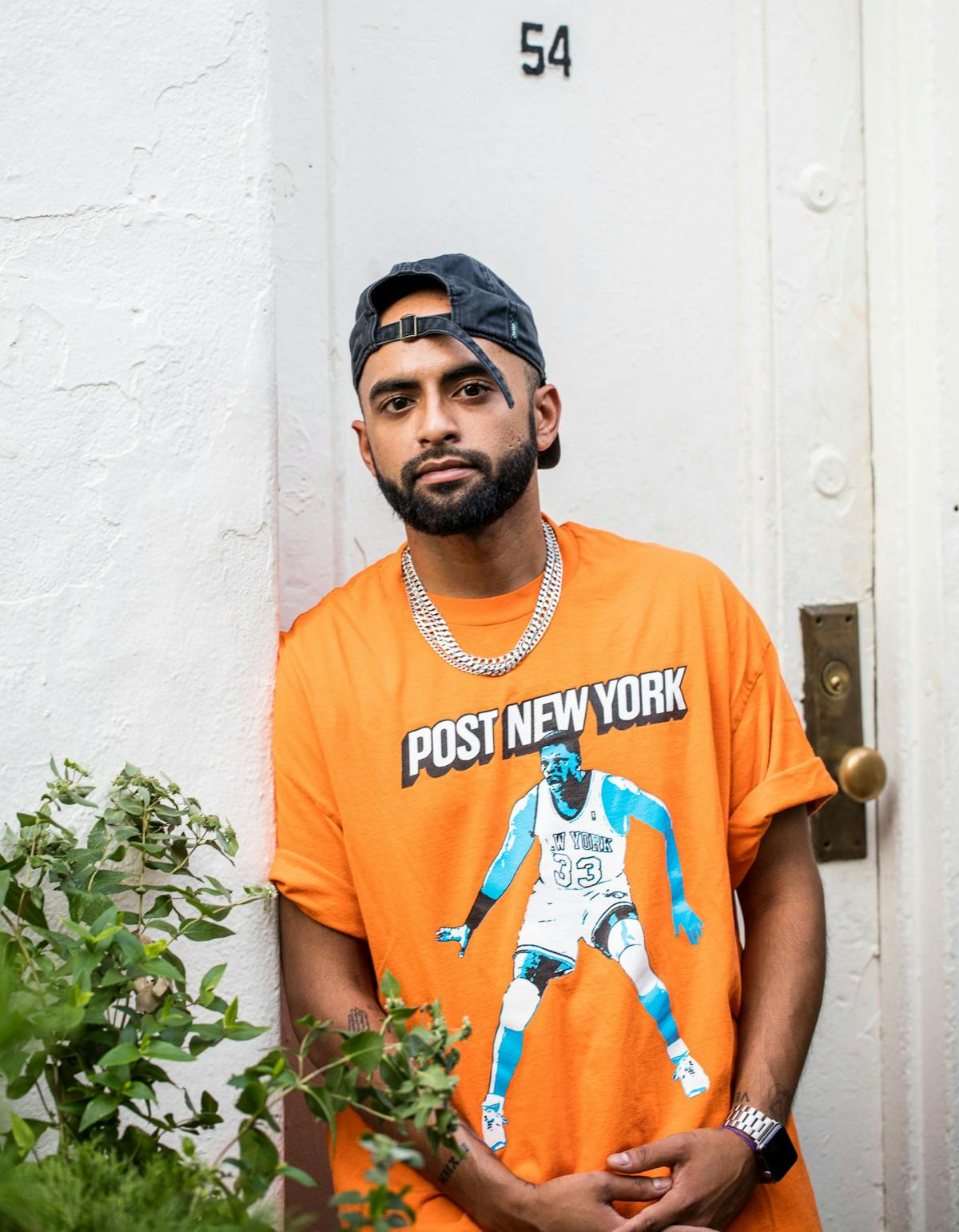 a man in orange shirt in front of a building