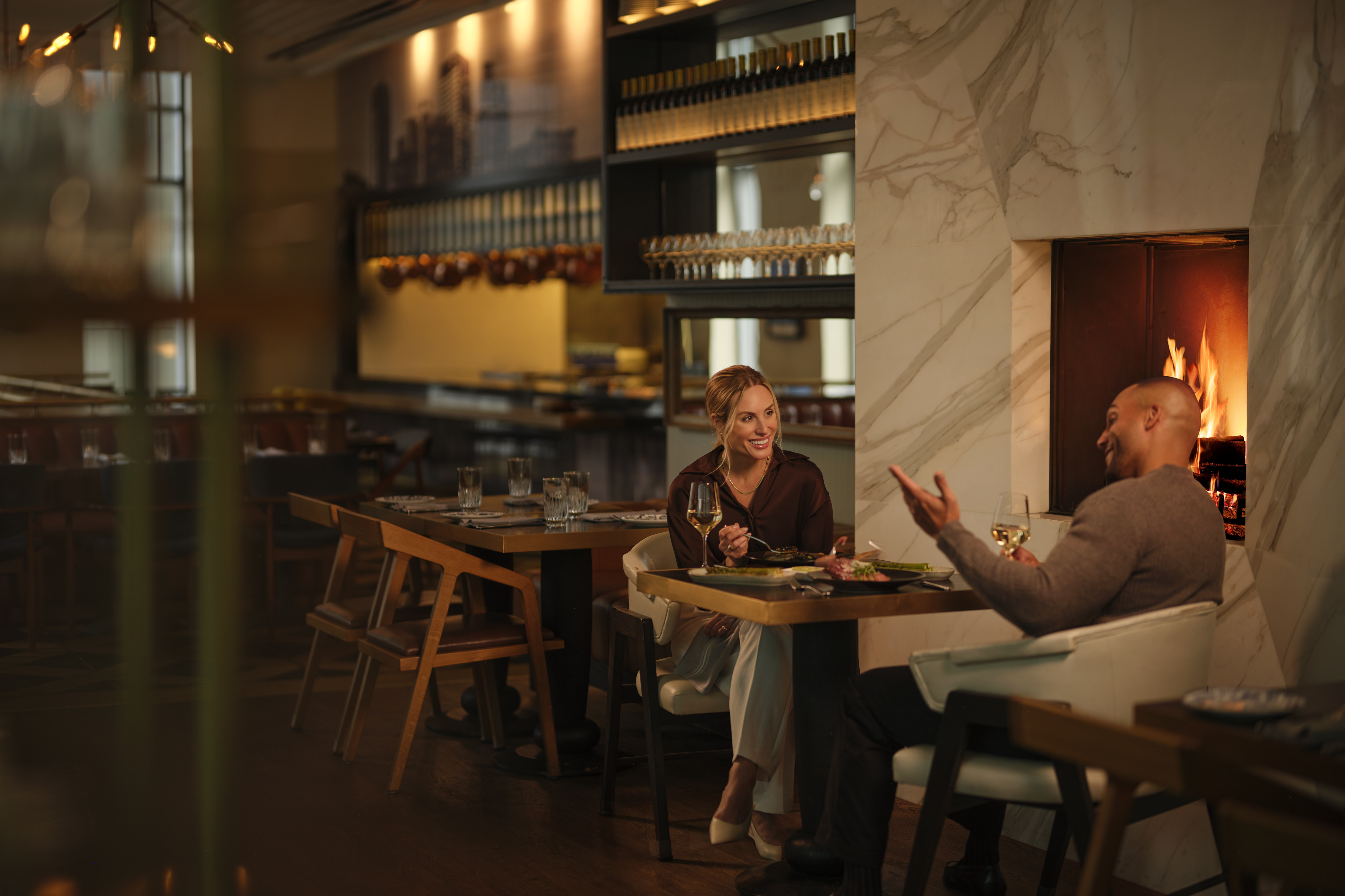 a man and woman sitting at a table with wine glasses