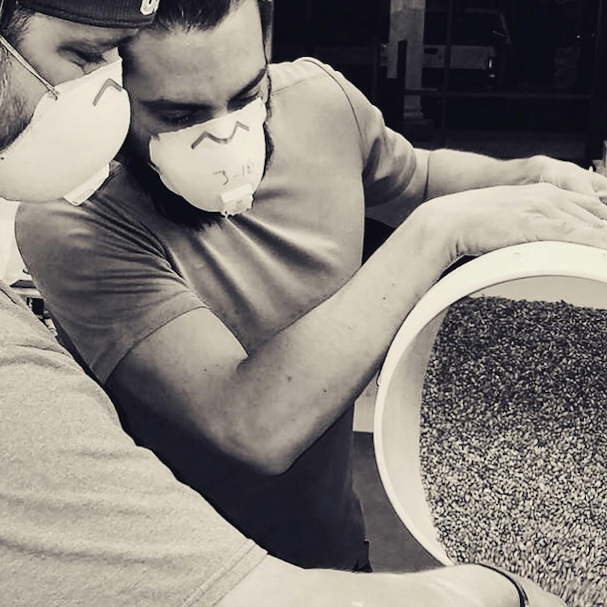 two men pouring seeds on a bottle