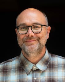 a man, Ron Boyd, wearing glasses and smiling at the camera