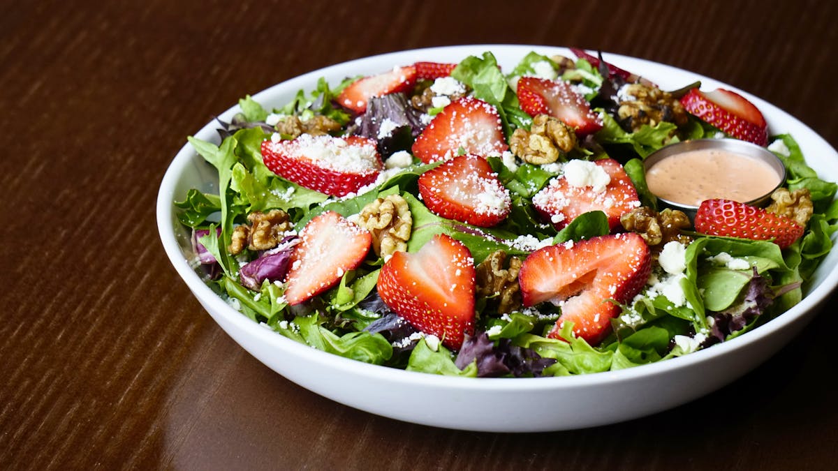 strawberry fields salad with fresh greens, strawberries, walnuts, feta cheese, and vinaigrette