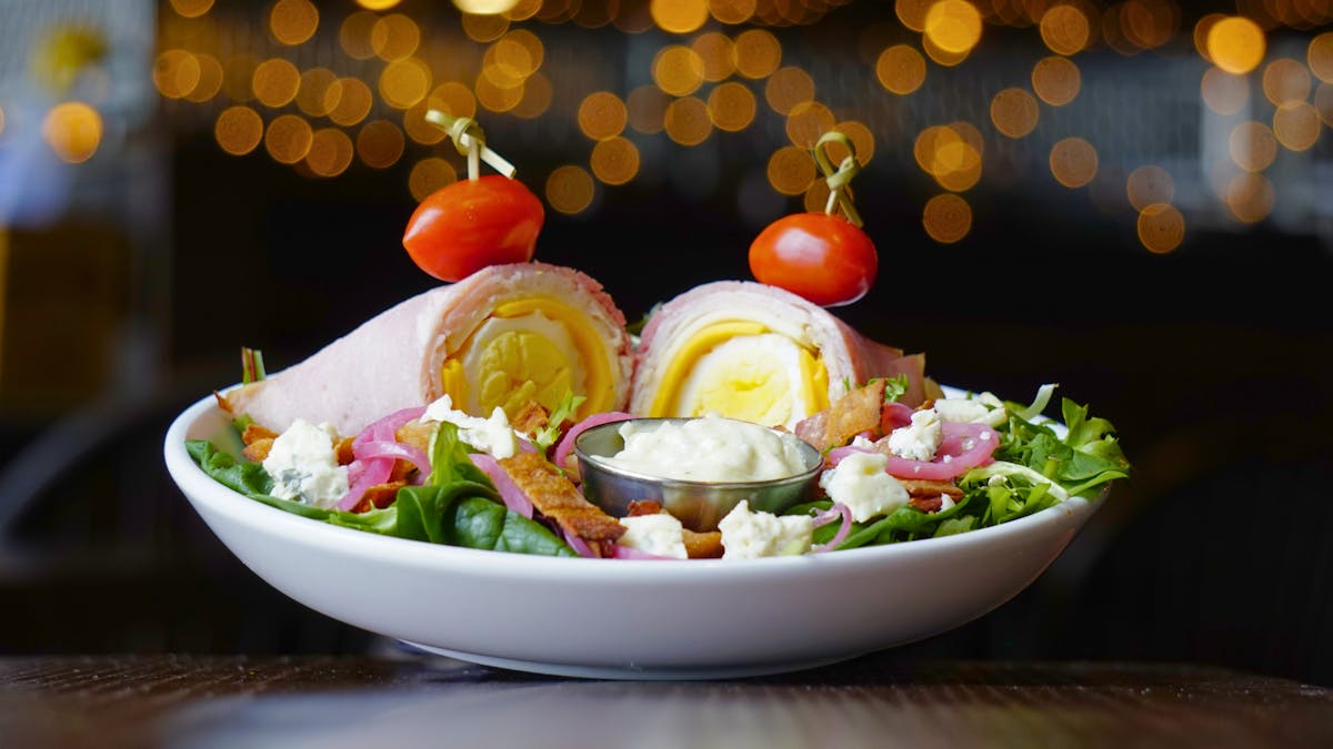 fresh cobb salad with bacon and blue cheese crumbles, hard boiled egg, ham, turkey, and cheese