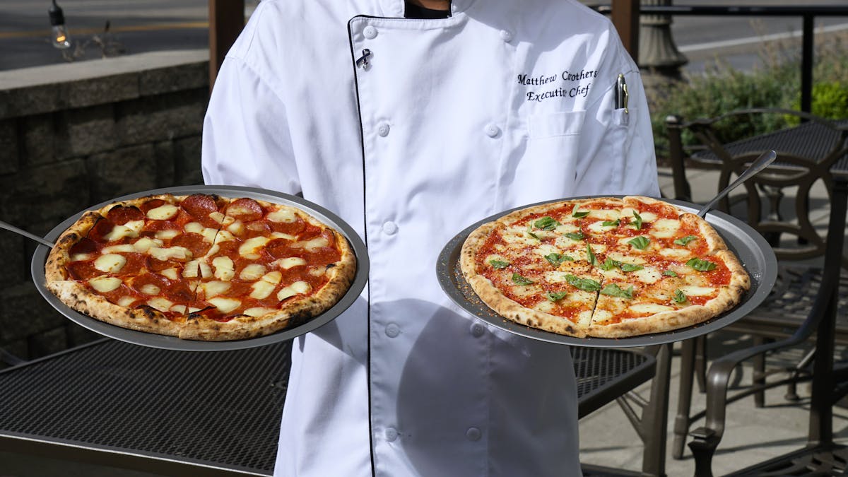 chef holding two Neapolitan pizzas