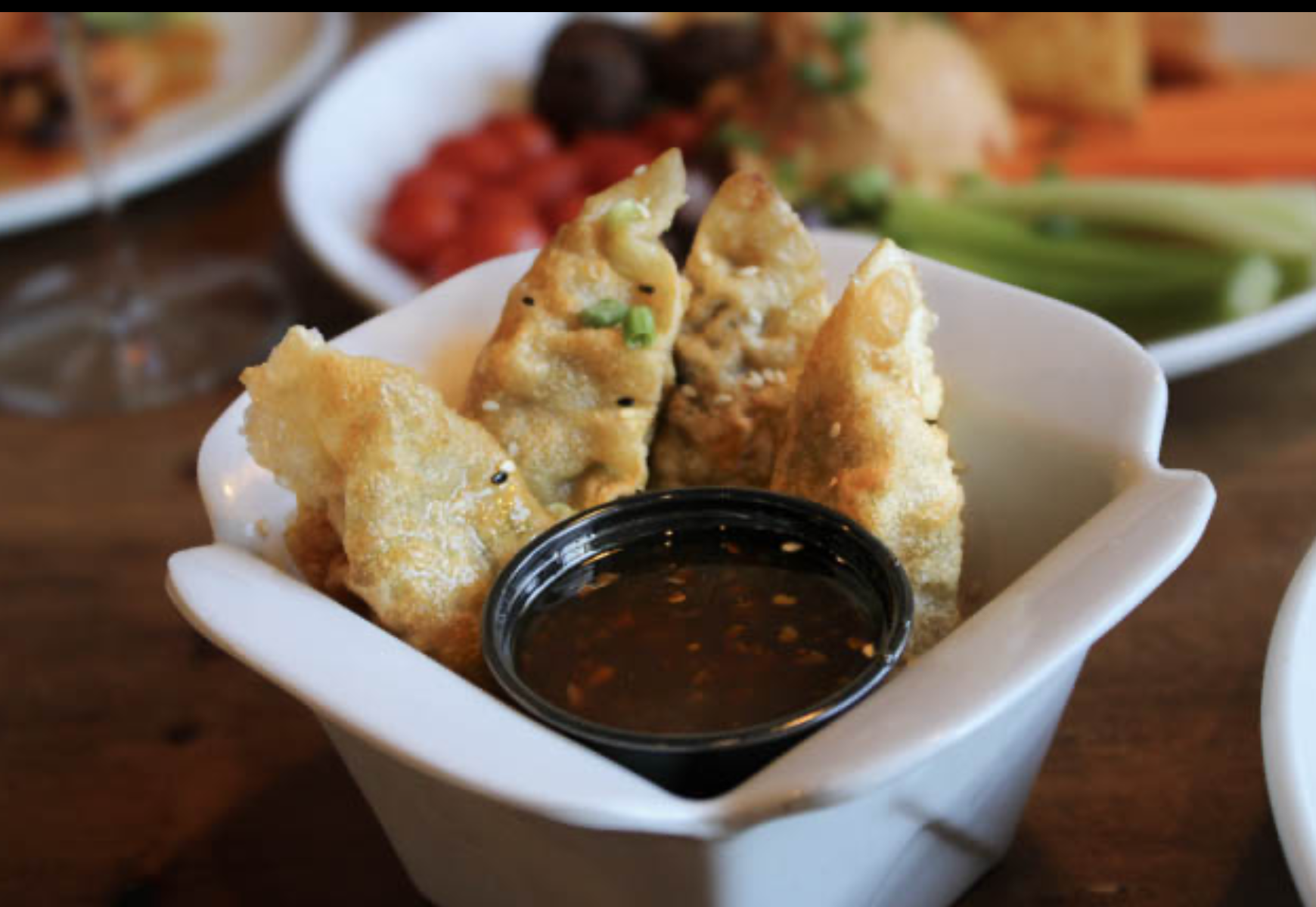 a bowl of fried dumplings with dipping sauce