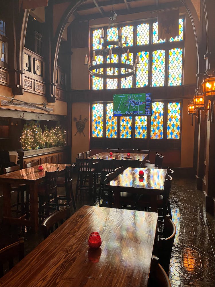room with empty tables, a stained glass wall, and a tv hanging in front of it