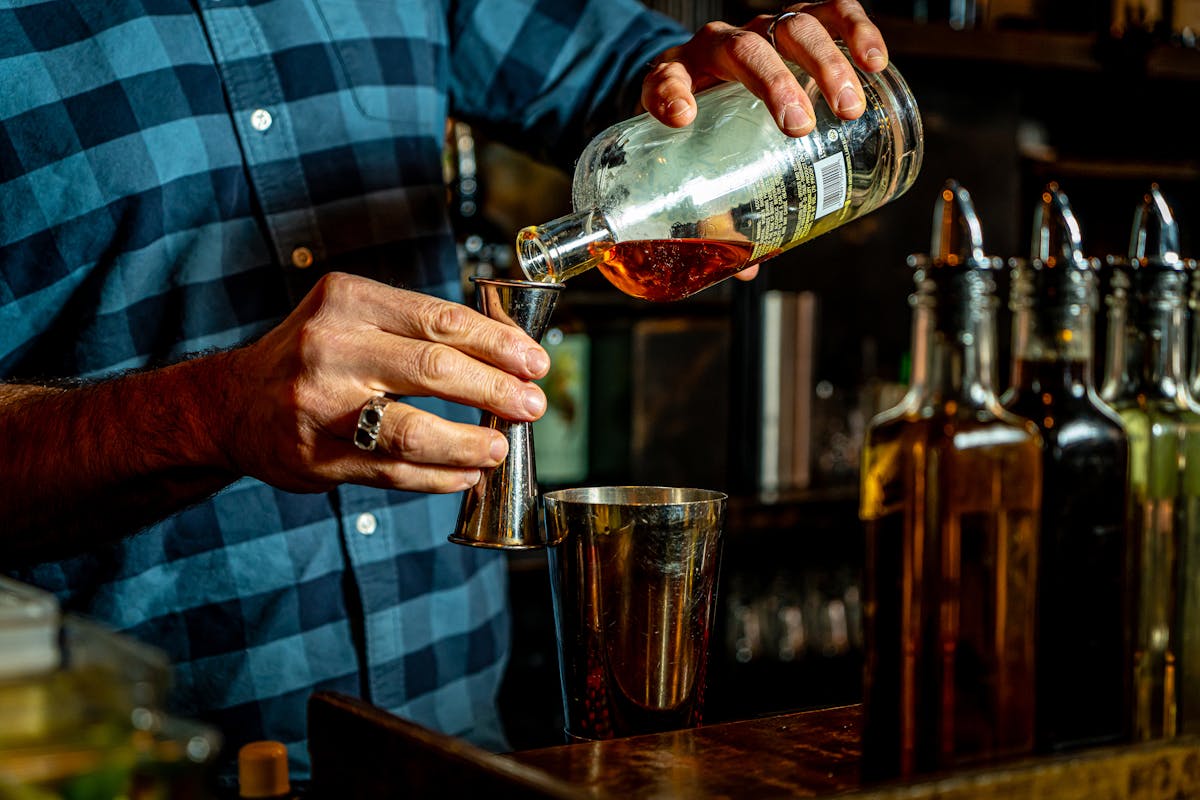 The bartender pours a glass of whiskey.