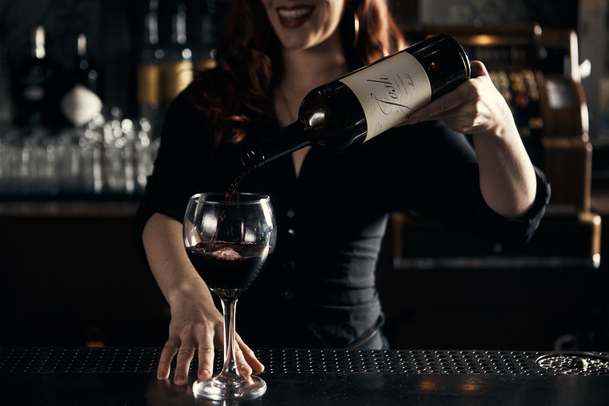 a person serving a glass of wine 