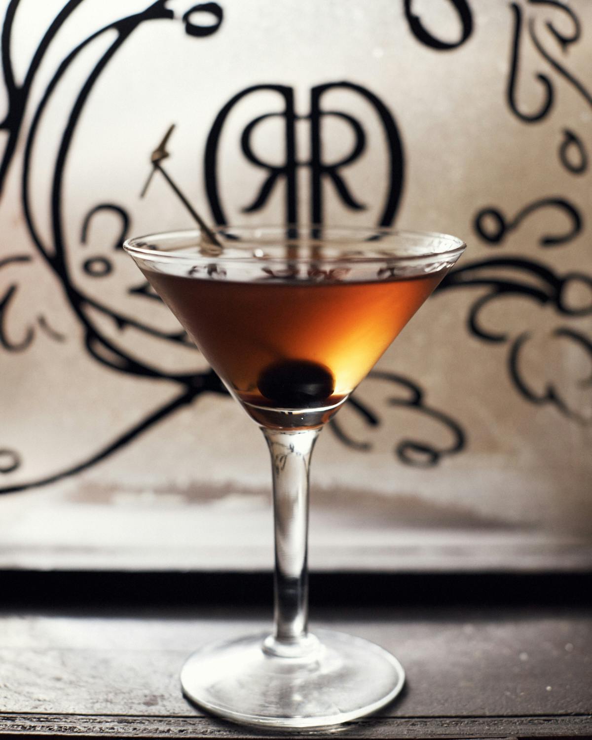 a cocktail glass with an olive inside