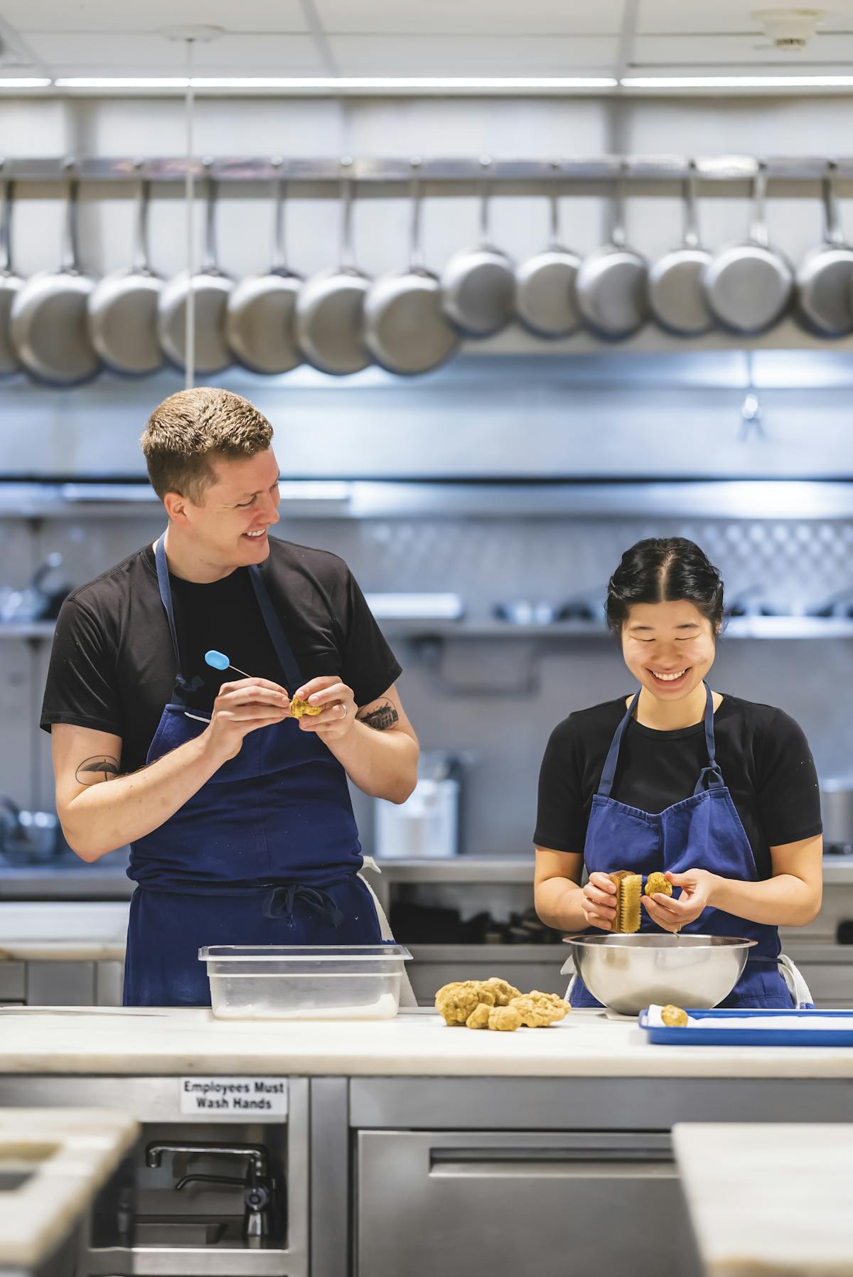 a man and woman preparing food in a kitchen