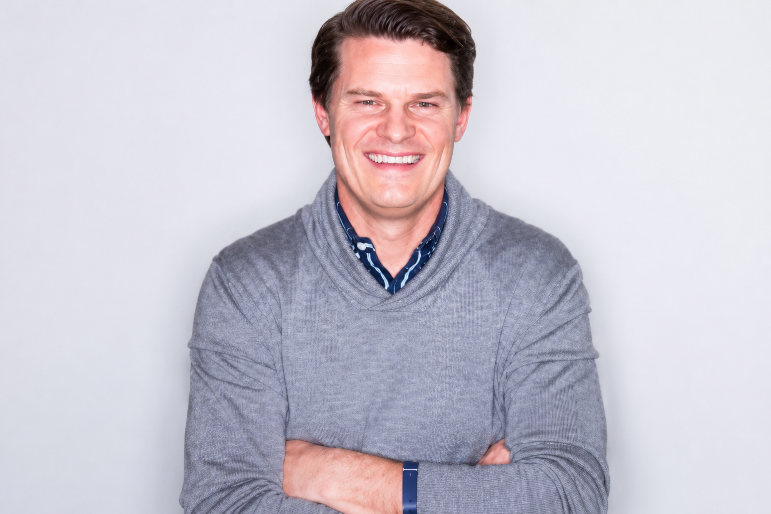 a man smiling with arms crossed