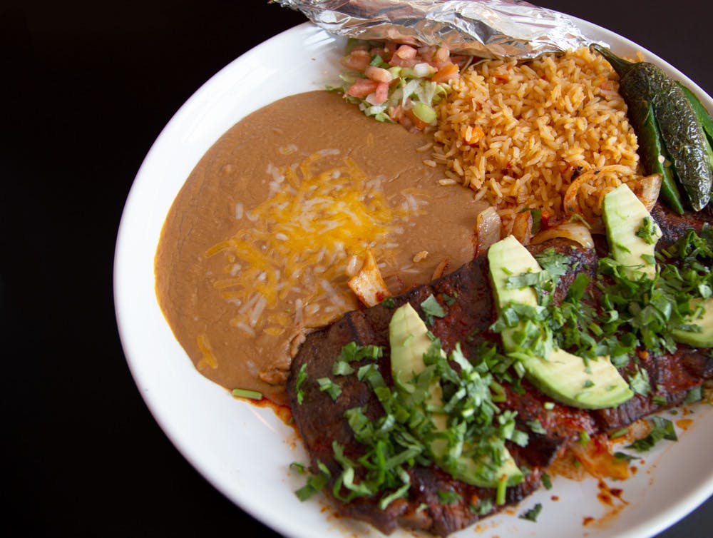 a white plate topped with rice meat and vegetables