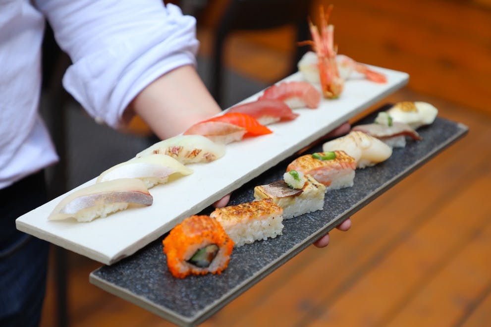 a pizza sitting on top of sushi on a table