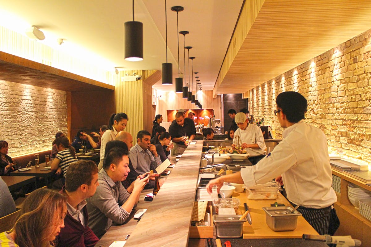 People eating inside JaBistro sushi restaurant while chefs make food