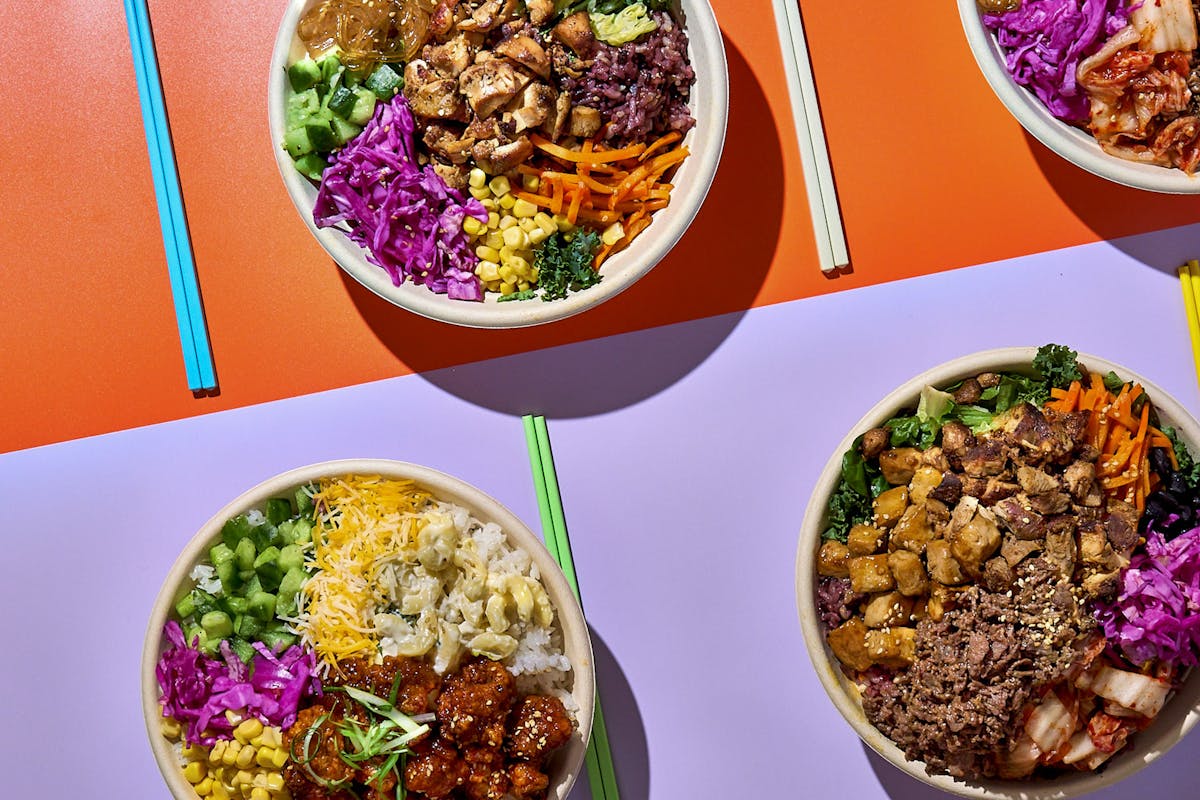 various rice bowls with meat and vegetables inside and chopsticks on the side
