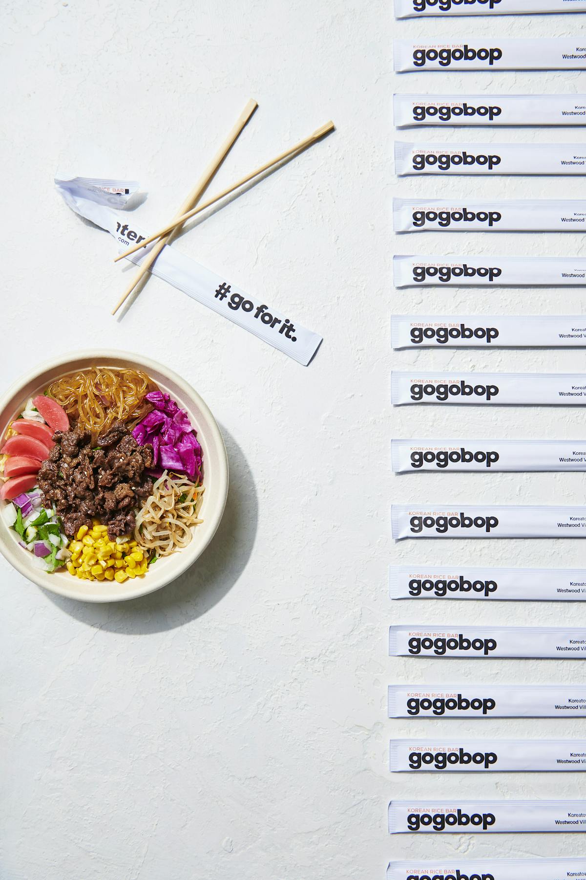 bowls filled with food and branded chopsticks with the Gogobop logo
