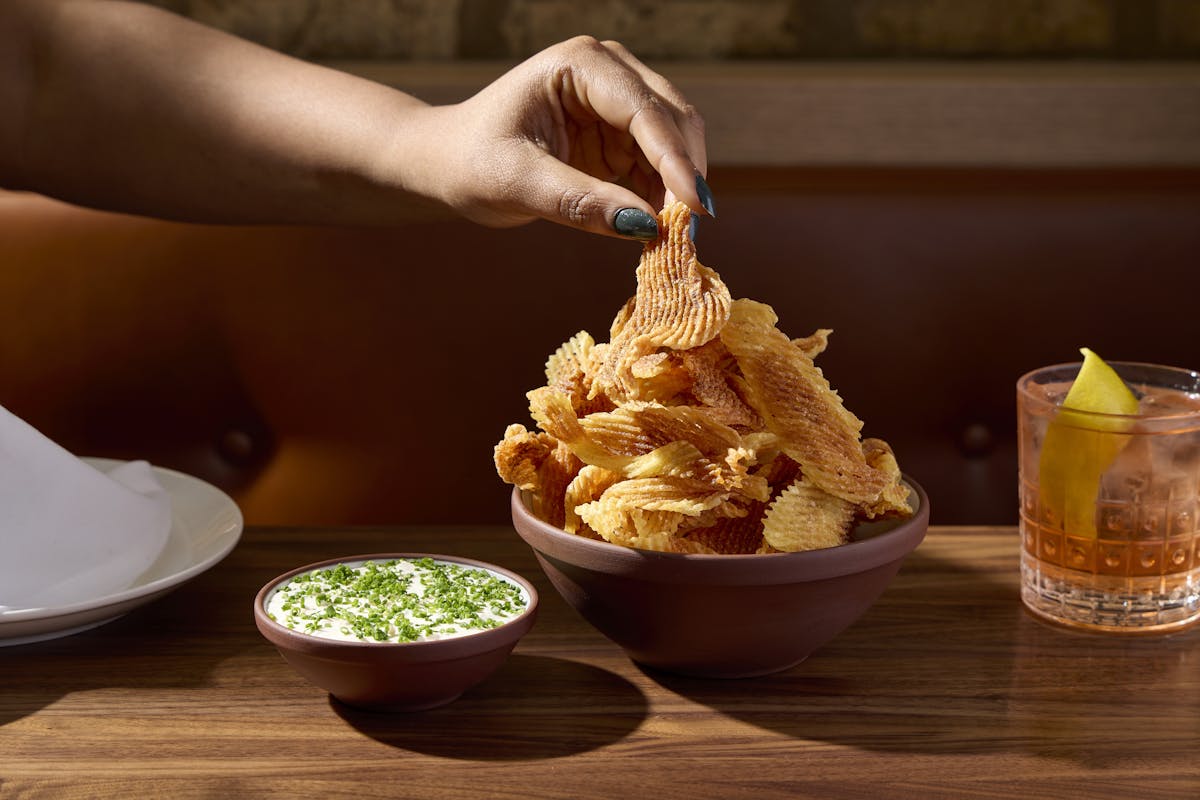 a person holding a plate of food on a table