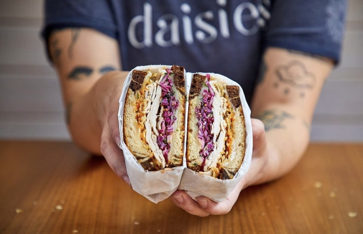 a hand holding a piece of cake on a table