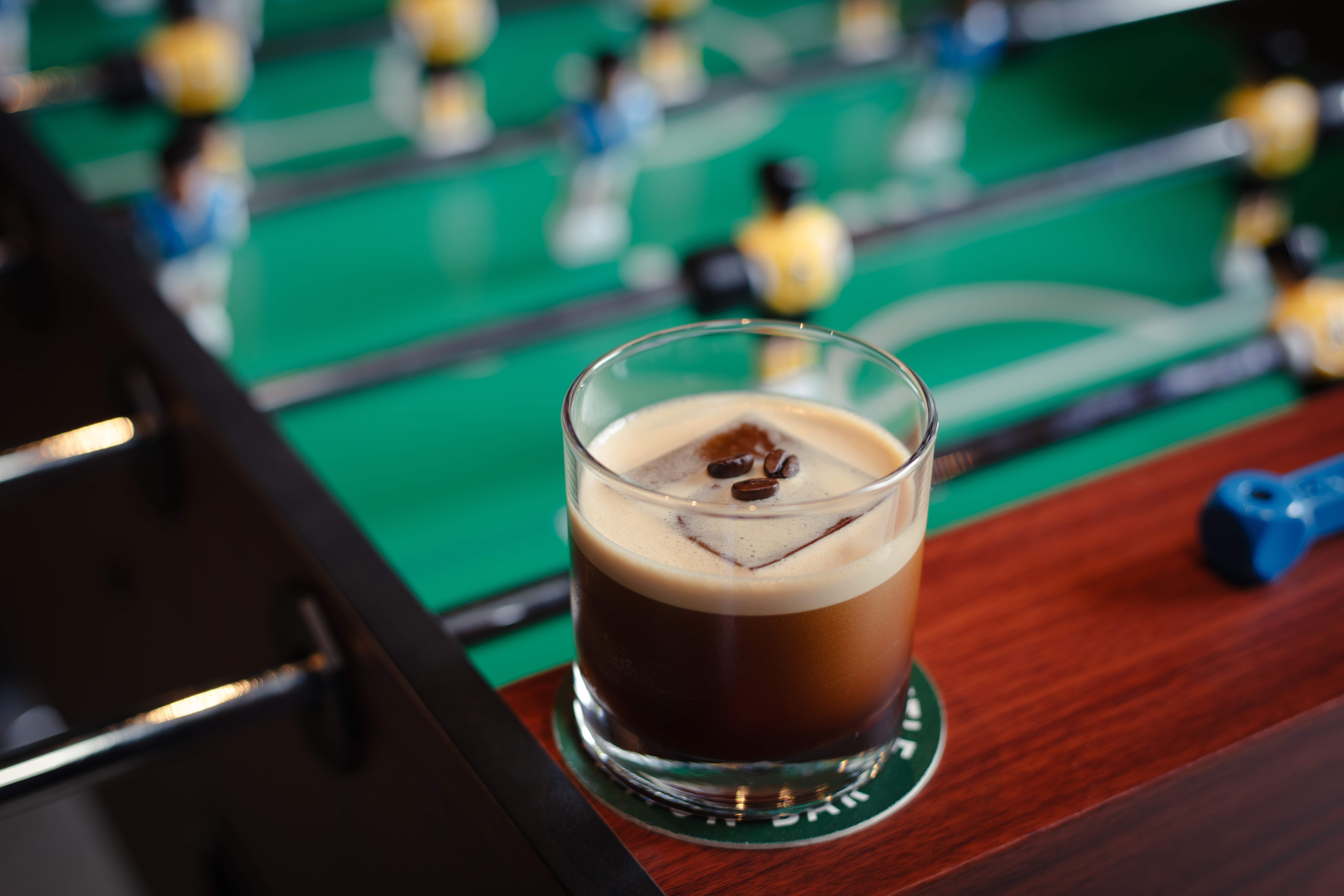 a glass of coffee with ice cubes and coffee beans on a table