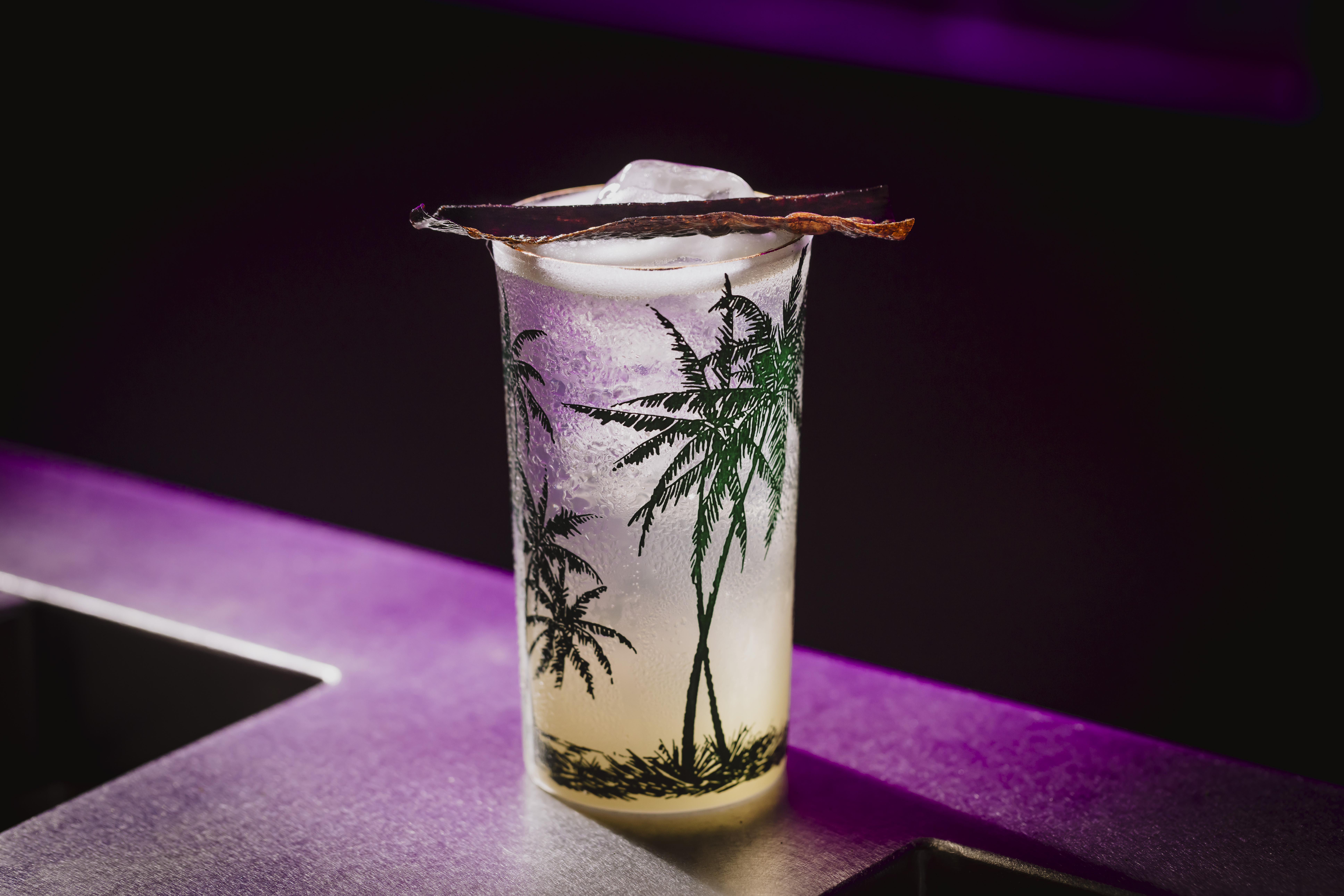 a glass with a drink and a piece of ice on it