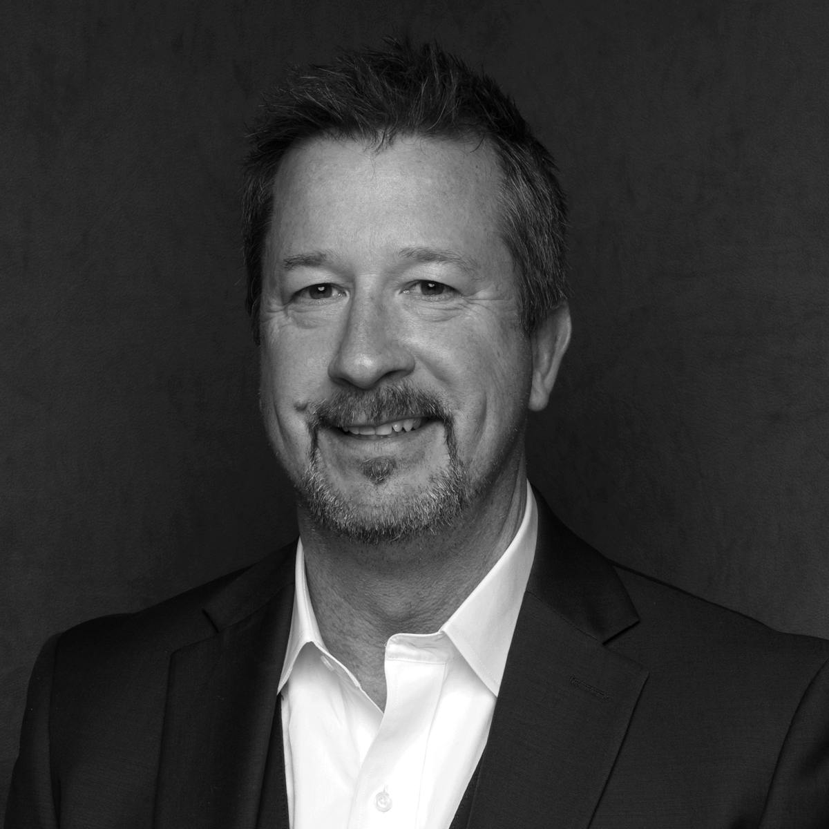 a man wearing a suit and tie smiling at the camera