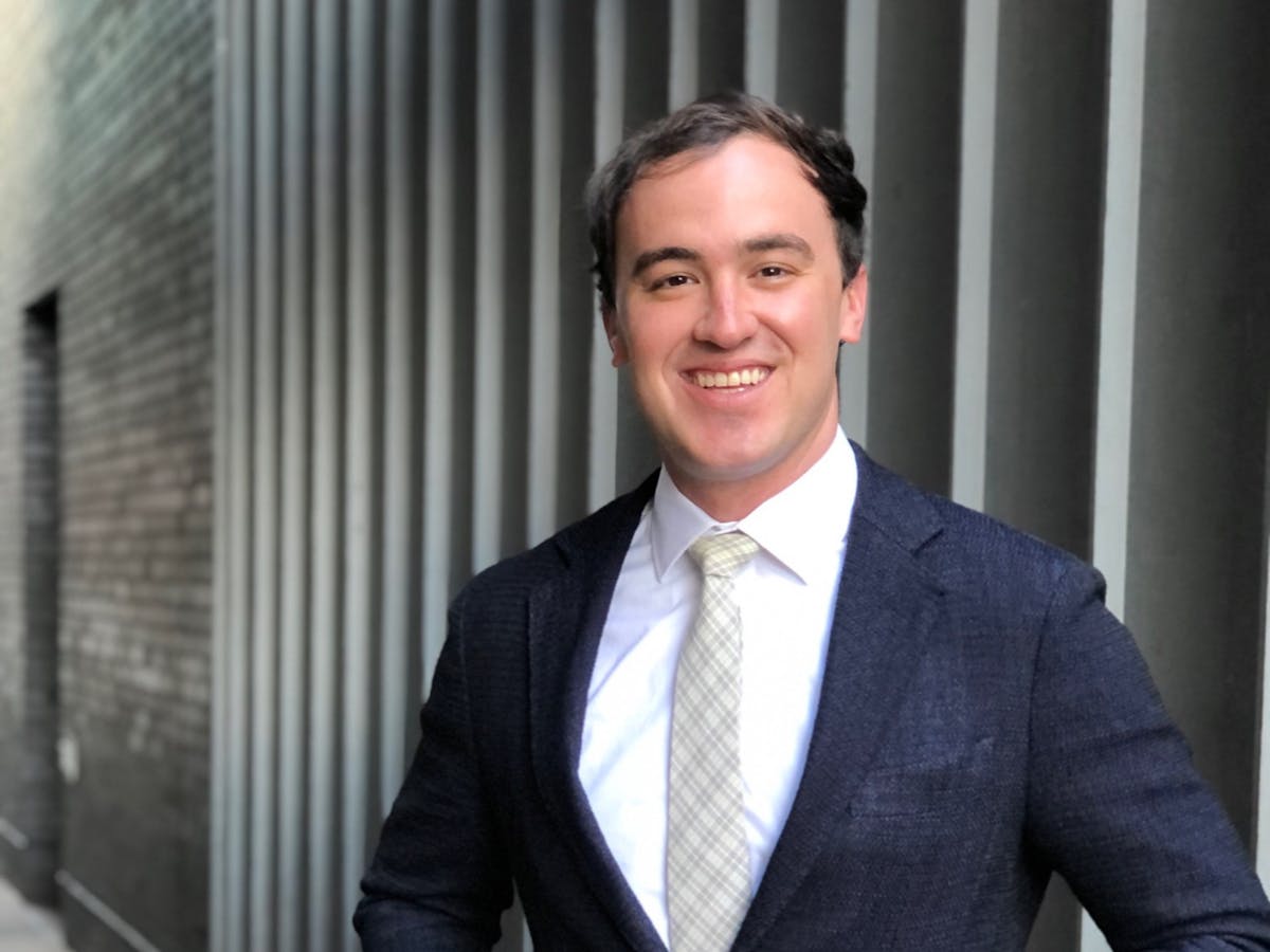a man wearing a suit and tie smiling at the camera