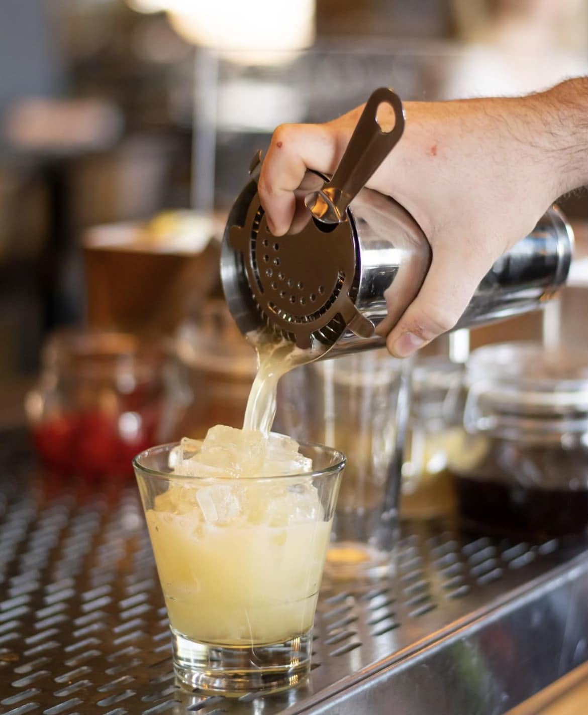 a person pouring a drink into a glass