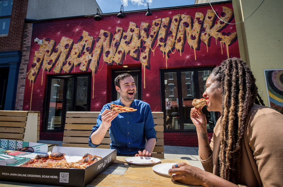 a group of people sitting at a table eating pizza