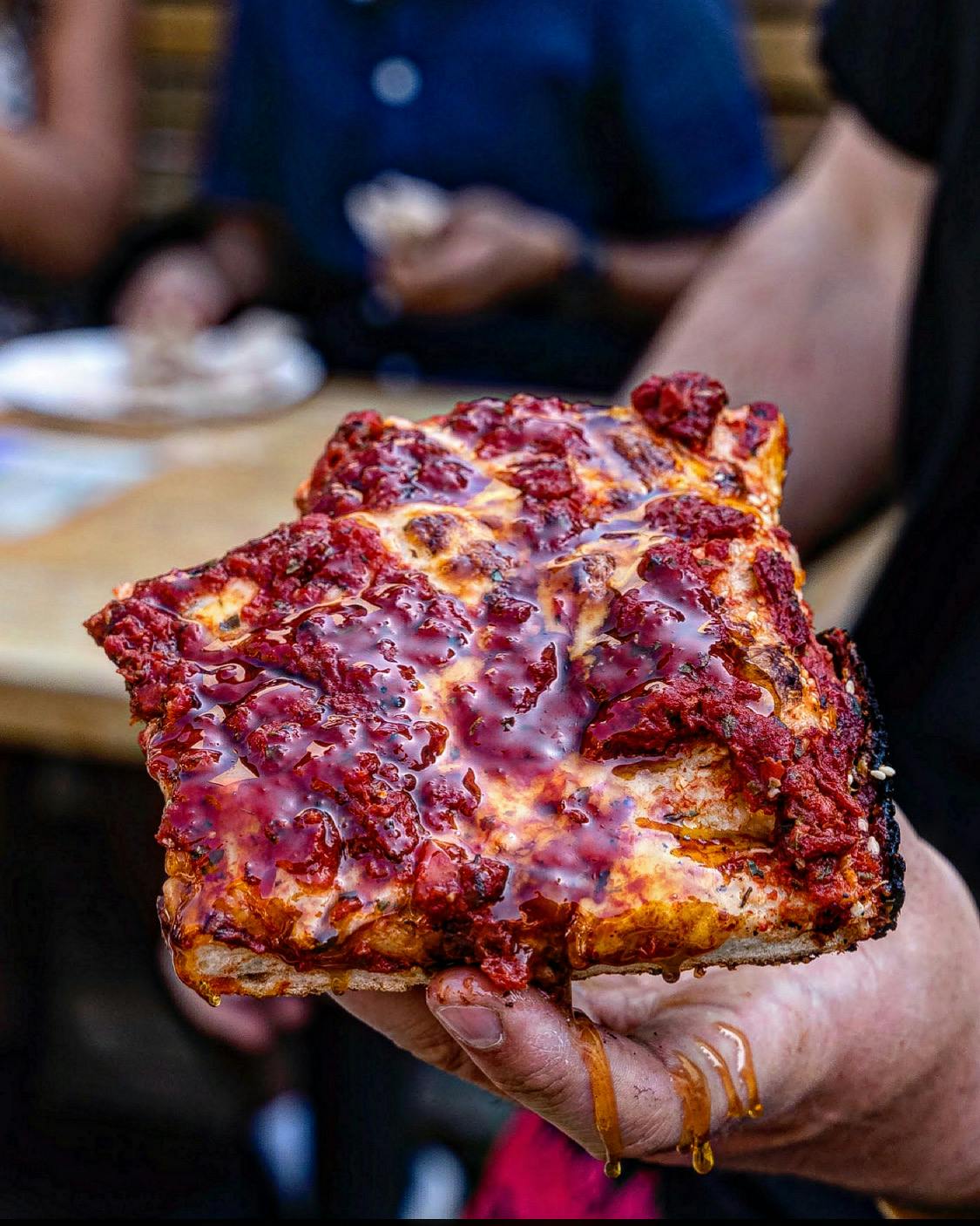 a hand holding a slice of pizza