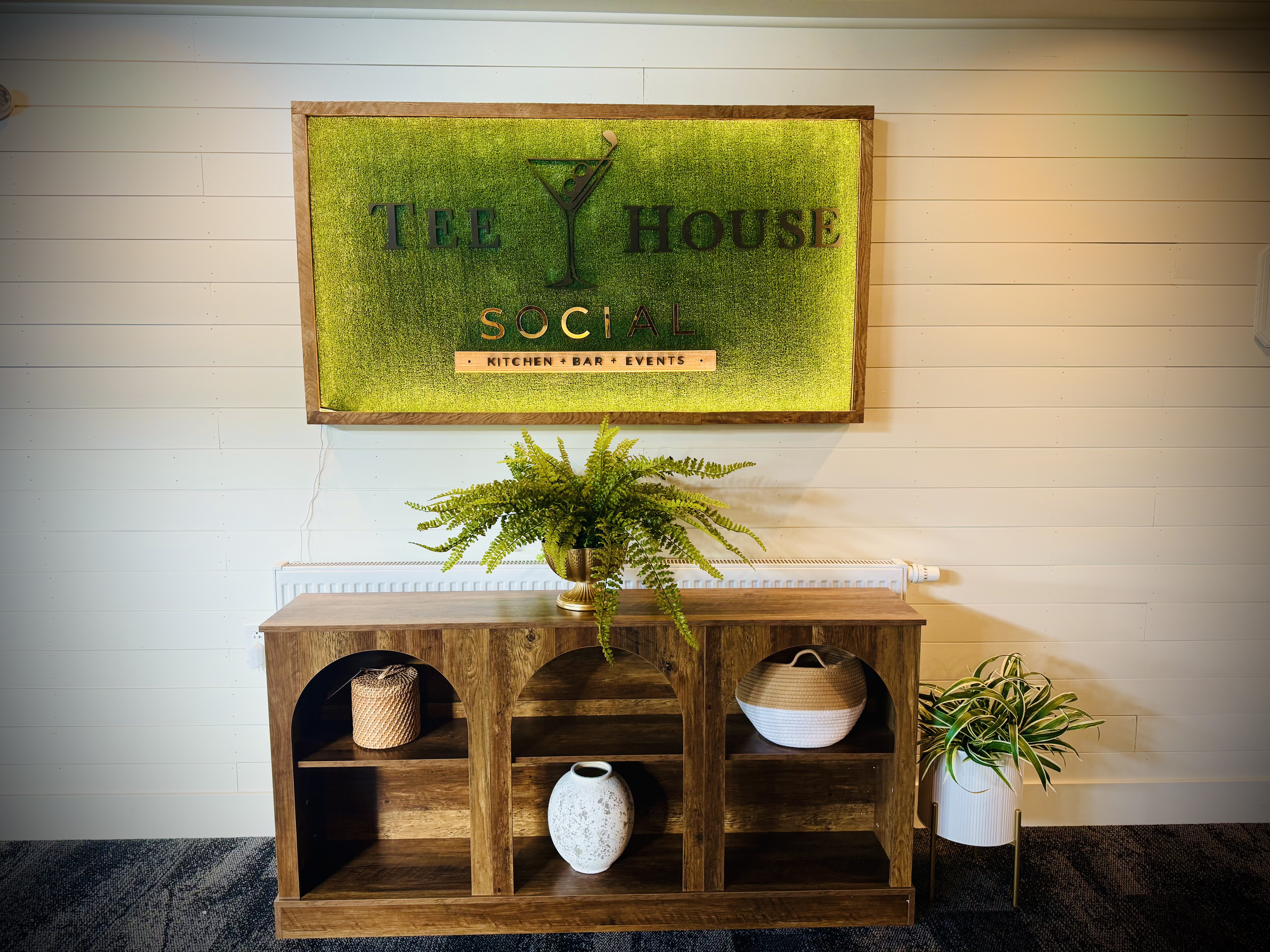 a shelf with plants and a sign on the wall