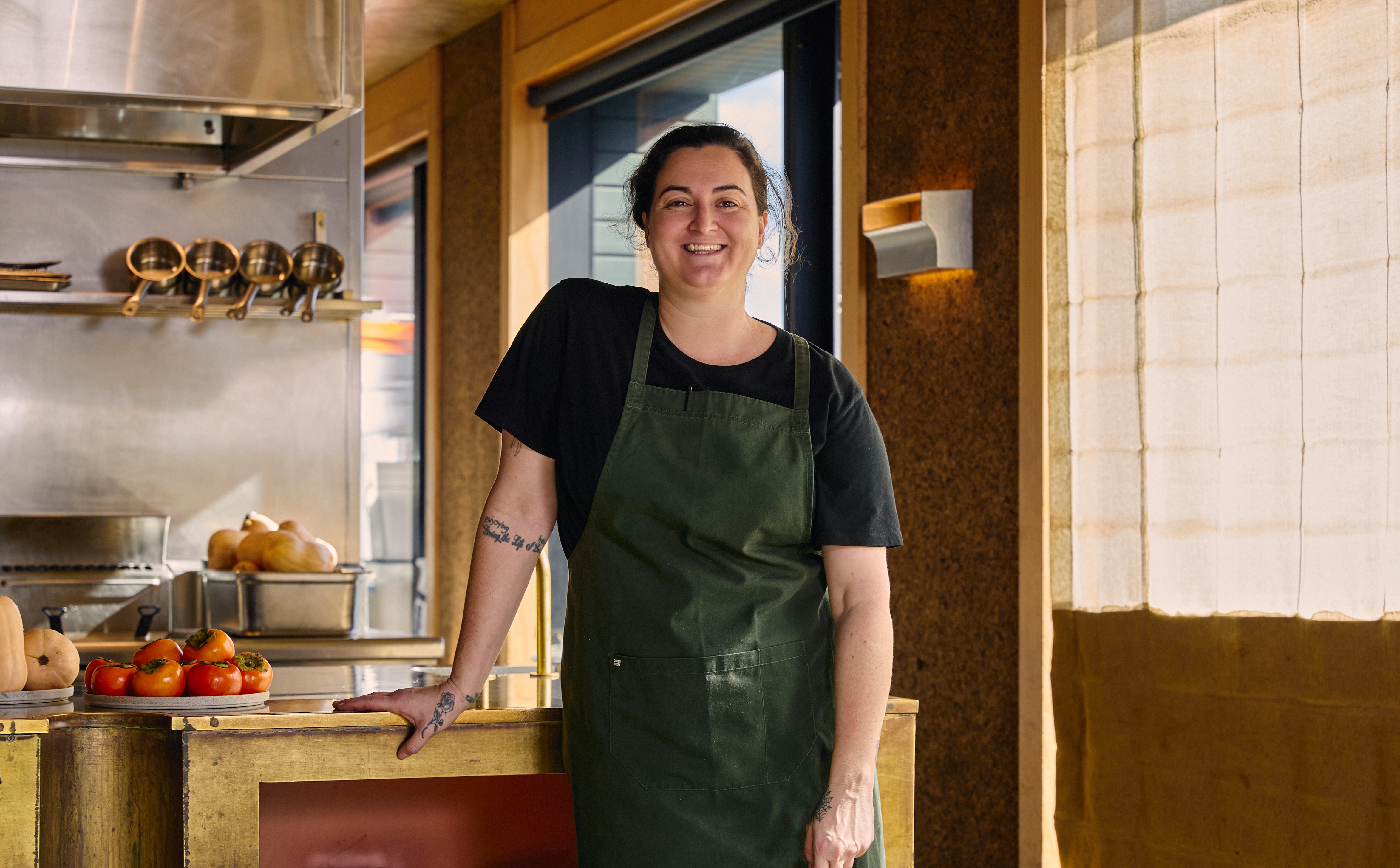 a woman wearing a green apron standing in a kitchen