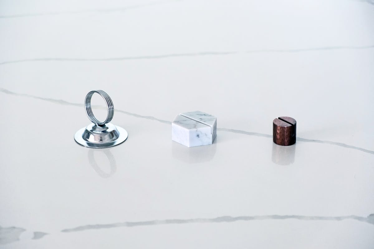 a chrome QR code sign holder, a marble holder, and a hammered copper holder