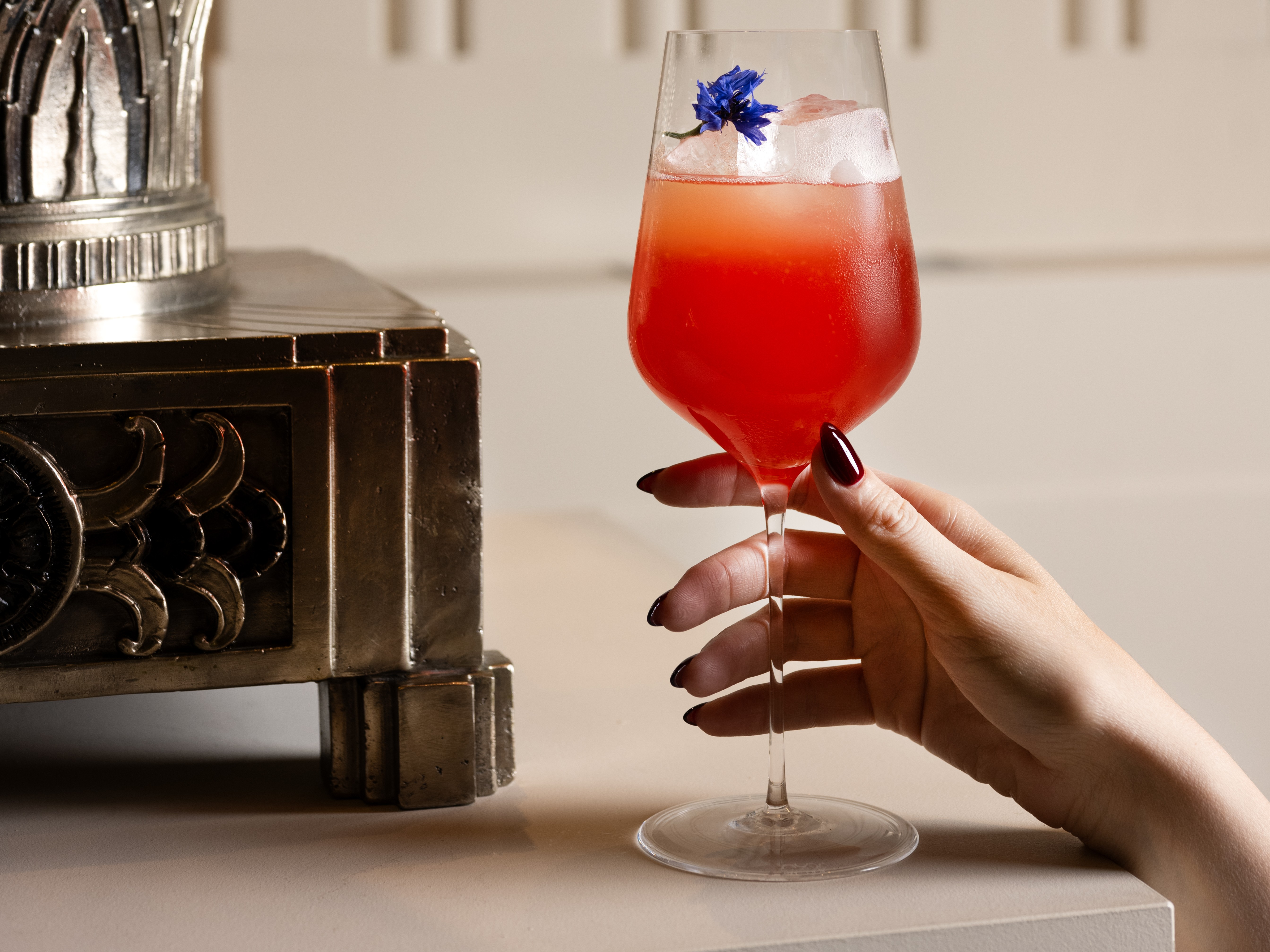 a hand holding a glass of red liquid