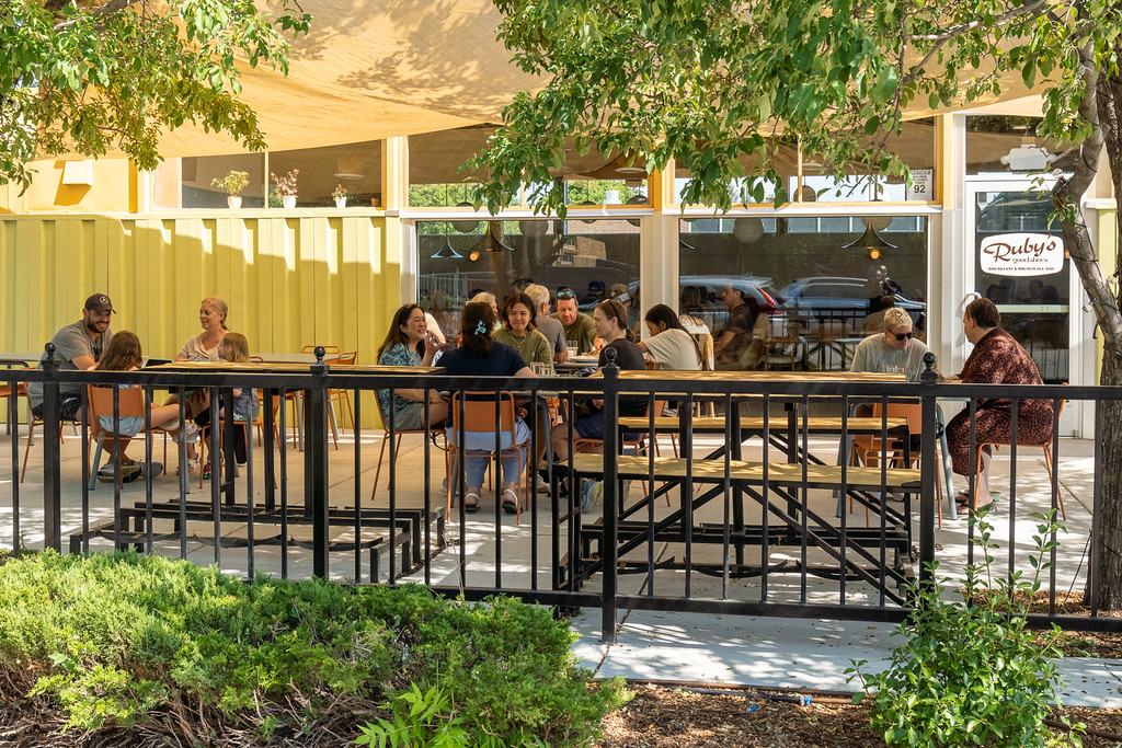 a group of people sitting at a table in front of a fence