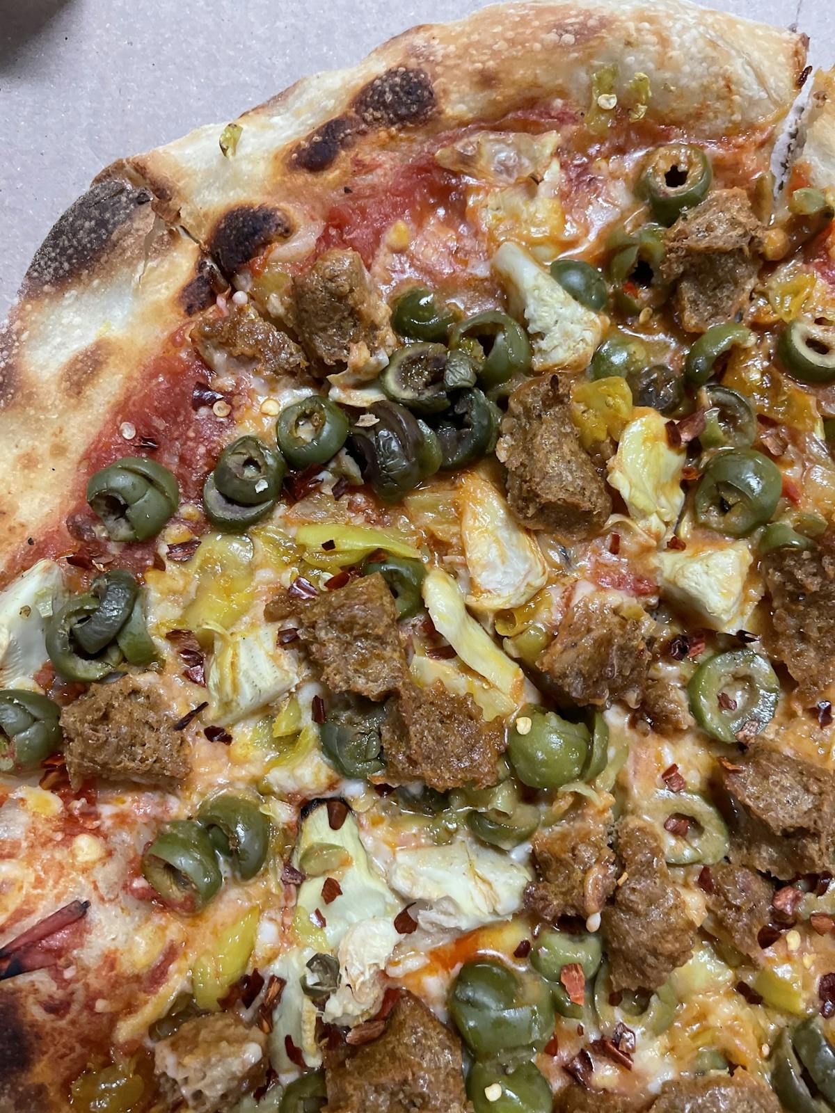 A delicious pizza topped with savory meat, black olives, and melted cheese, ready to be enjoyed
