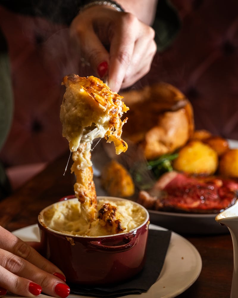 spooning some cauliflower cheese with a sunday roast