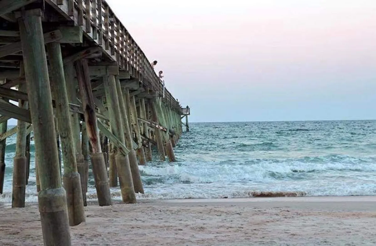 a beach with a pier in front of a body of water