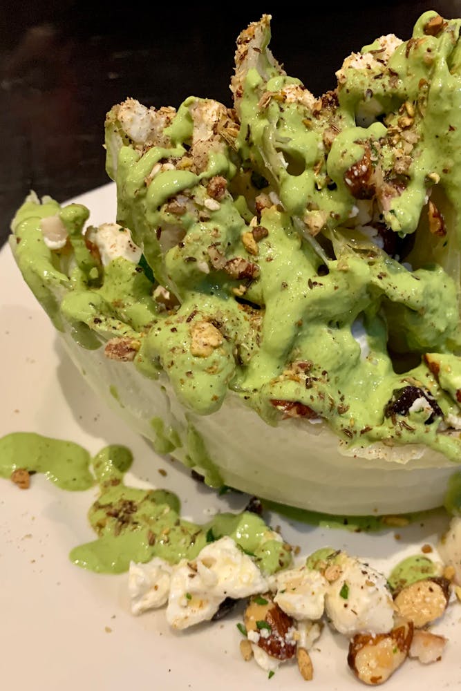 a grilled wedge salad with dressing and nuts