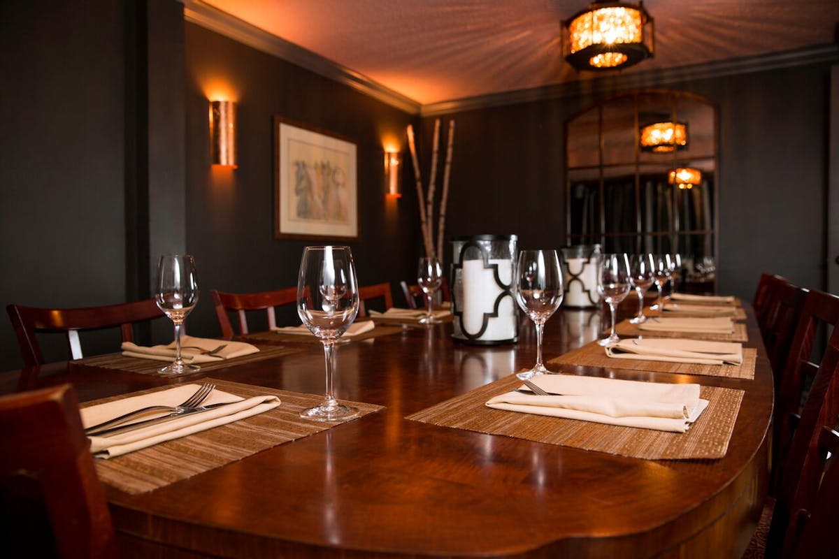 the interior of a dining room with a table set with wine glasses and place settings