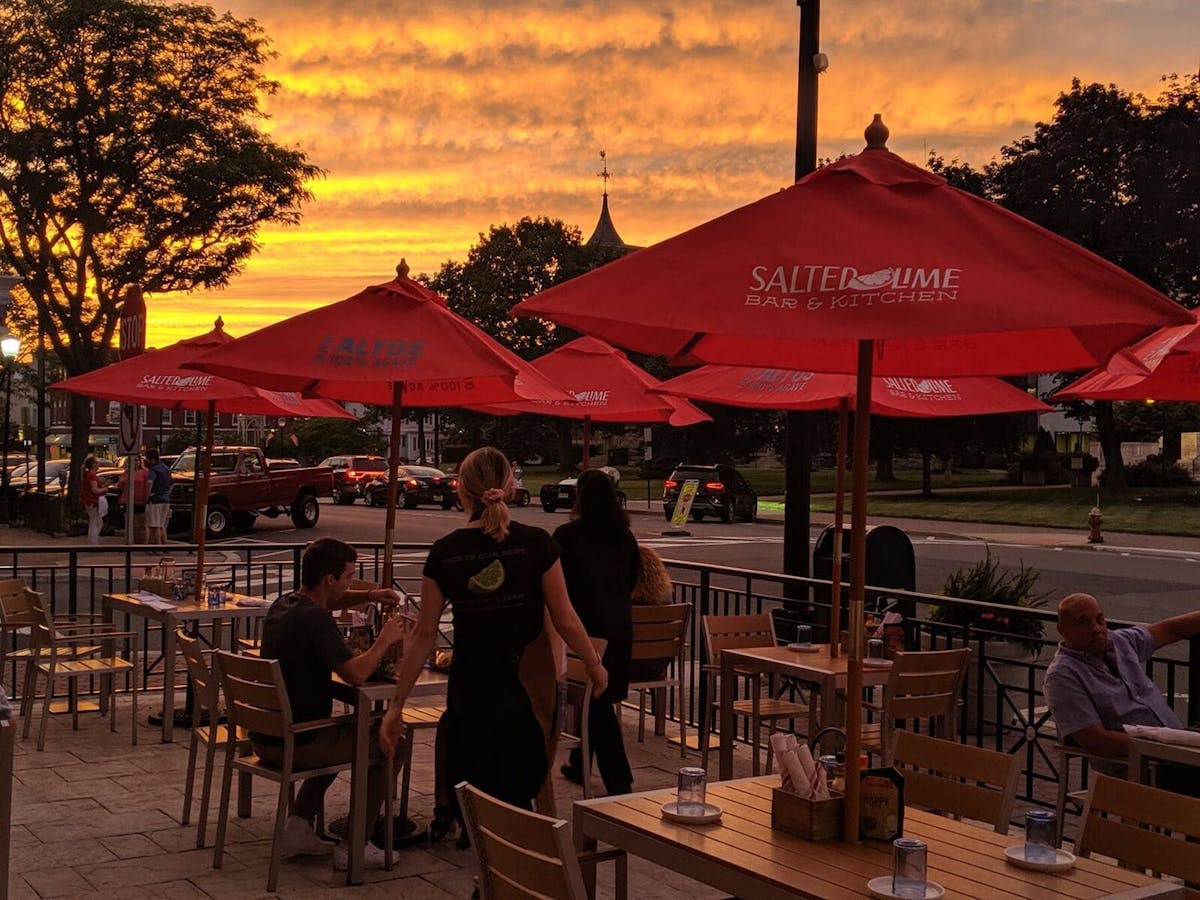 a group of people sitting at a table with an umbrella