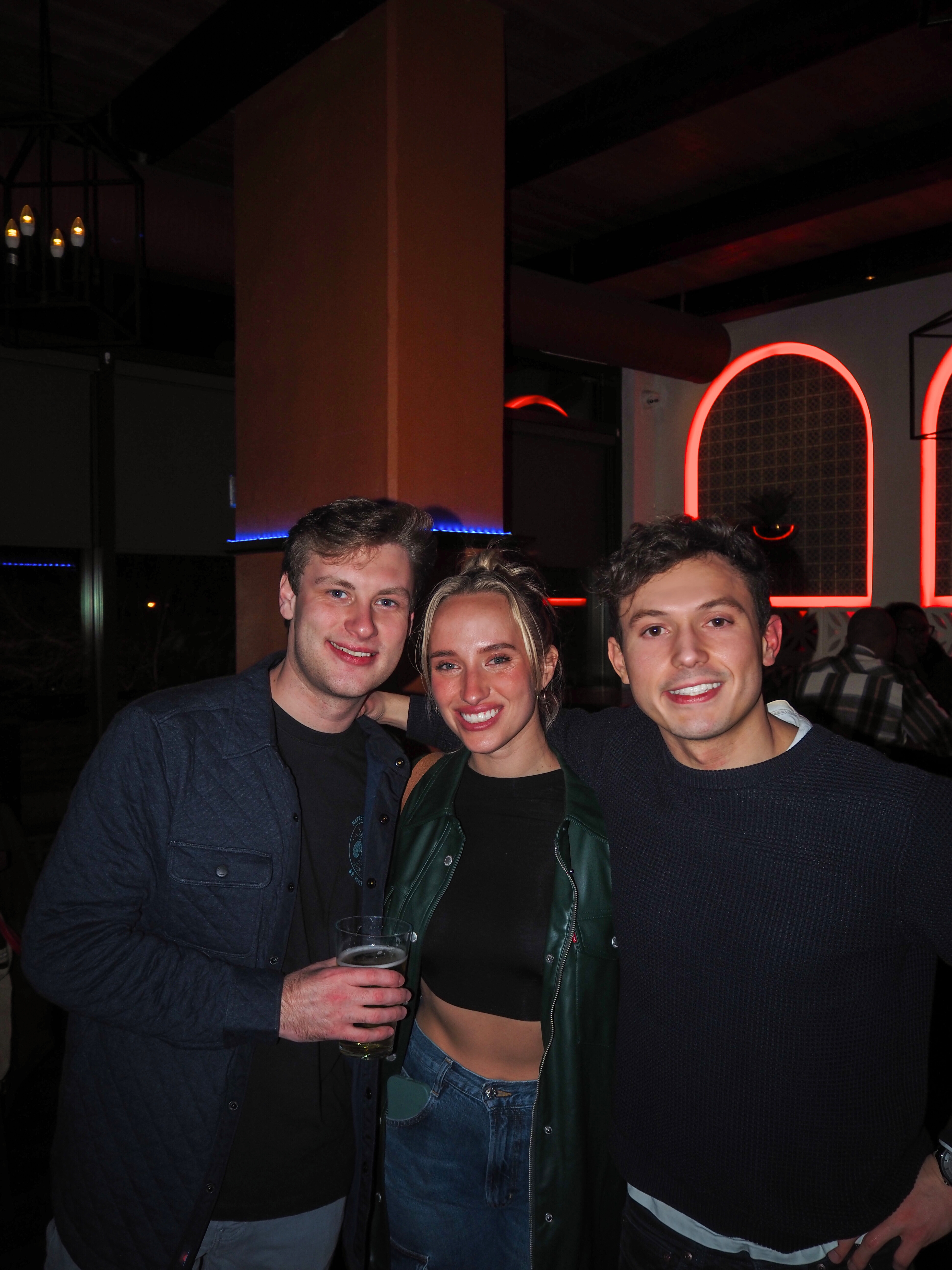 a group of people standing next to a wine glass posing for the camera