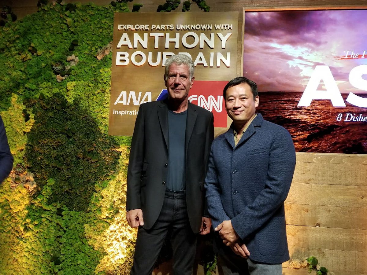 Anthony Bourdain standing in front of a sign