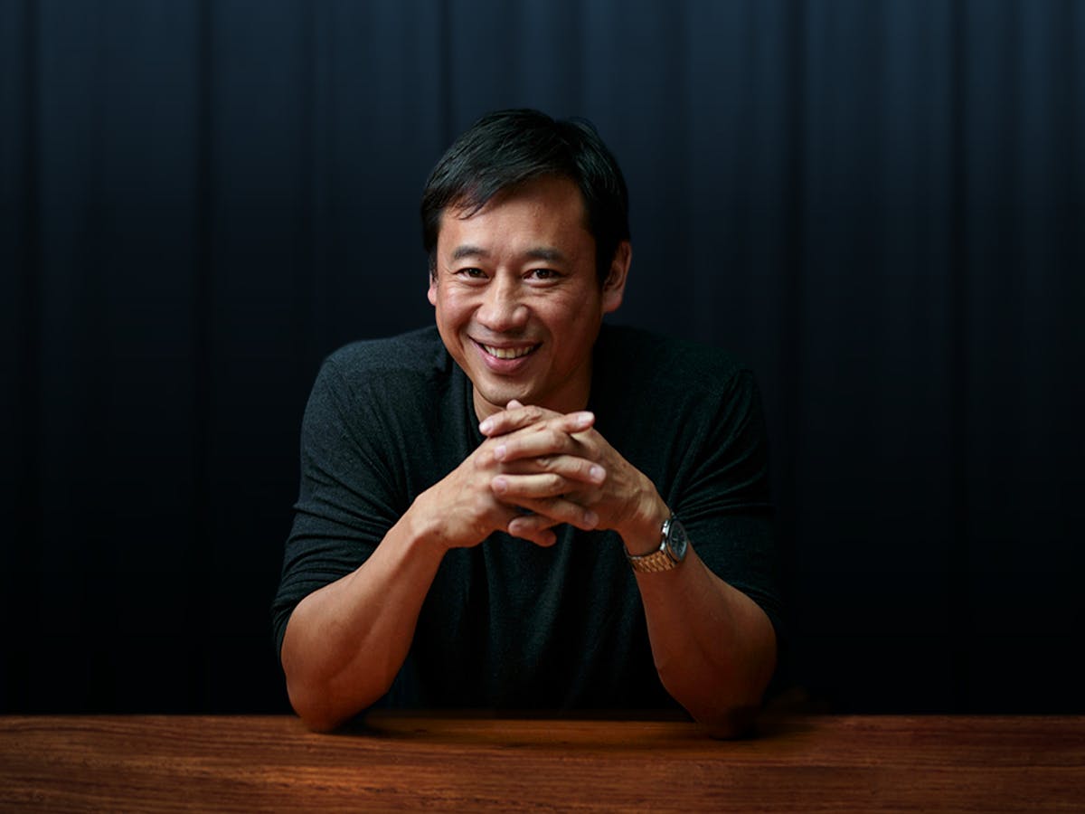 a person sitting at a table in front of a curtain